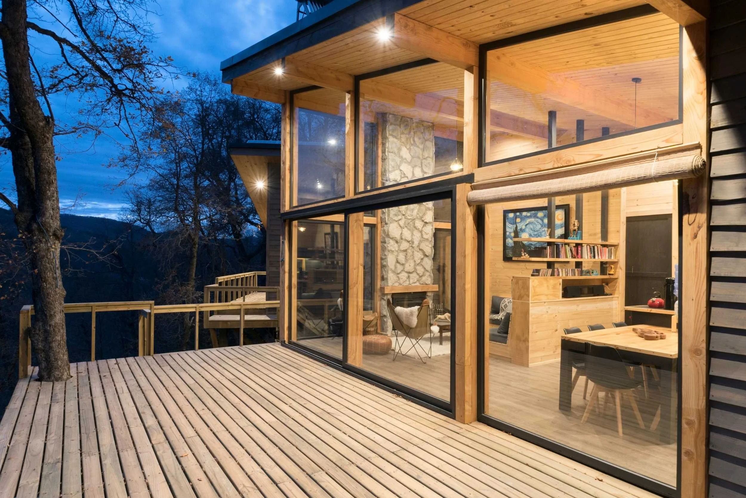 Terraza de madera de cabaña moderna al atardecer con vista al bosque
